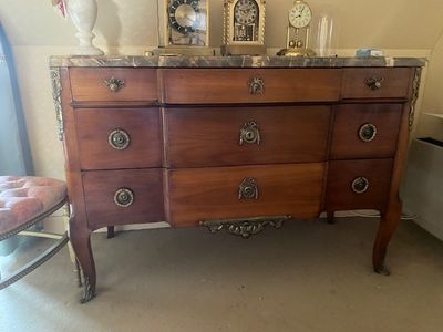 une commode avec un plateau en marbre et une chaise placée devant