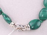 a close up of a necklace with green beads on a mannequin