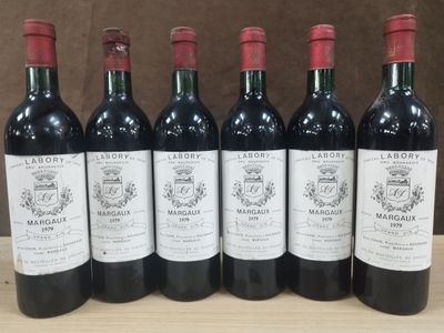 six bouteilles de vin rouge sont alignées sur une table en bois