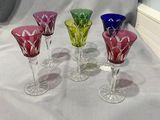 quatre verres à vin en verre de couleurs différentes posés sur une nappe blanche