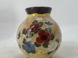 a yellow vase with flowers painted on it on a white surface