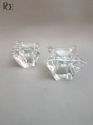 une paire de bougeoirs en verre transparent posés sur une surface blanche
