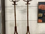 two wooden coat stands with hooks on them in front of a wall