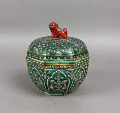 une boîte verte et dorée surmontée d'un oiseau
