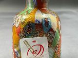 a multicolored glass vase with a sticker on it