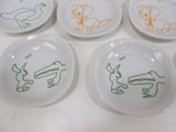 four white plates with drawings of animals on them on a table