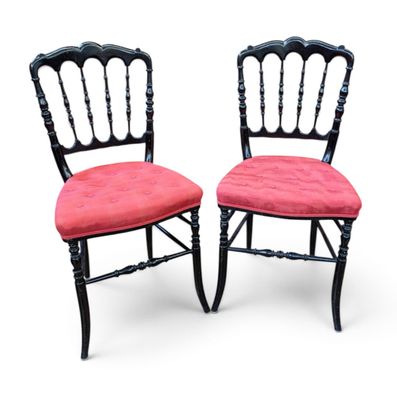 une paire de chaises noires avec des coussins rembourrés roses