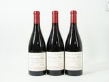 trois bouteilles de vin rouge posées l'une à côté de l'autre sur une surface blanche