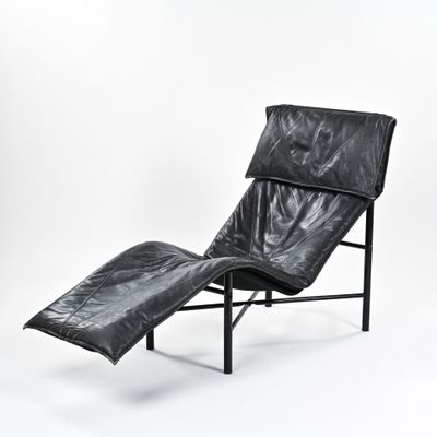 black leather chaise lounger with black metal frame and foot rest