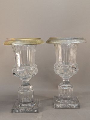 pair of clear glass vases with gold rims sitting on a table