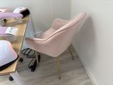 a pink chair sitting in front of a desk with a lamp