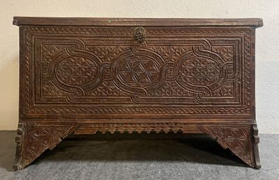 un vieux coffre en bois posé sur un sol recouvert de moquette