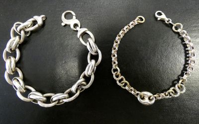 deux bracelets en argent sur un fond noir, avec une chaîne en argent