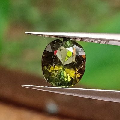 a close up of a green and yellow diamond being held by a pair of pliers