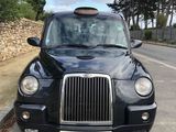 black cab parked on the side of the road in front of a stone wall