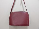 maroon leather purse hanging on a wall with a white background