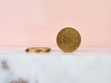 a gold coin sitting on top of a marble counter next to a pink wall