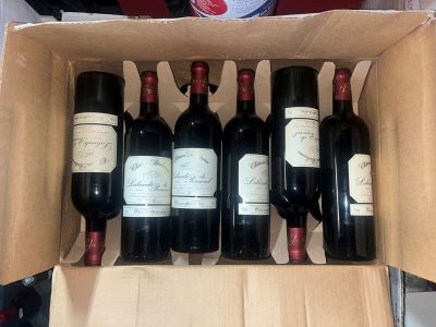 six bouteilles de vin sont posées sur une table dans un carton