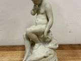 une statue représentant un garçon assis sur un rocher
