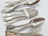 six fourchettes et cuillères en argent sont disposées sur une surface blanche