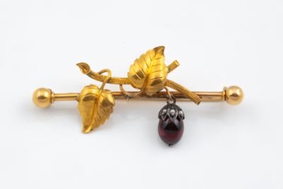 an image of a gold and garnett broochle with leaves on it