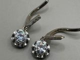 pair of diamond earrings on a white surface with a white background