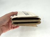 a person holding an open newspaper in their hand