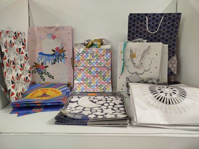 de nombreux sacs en papier posés sur une table, à côté d'un ventilateur