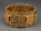 Gros plan sur un bracelet en or orné d'une pièce de monnaie