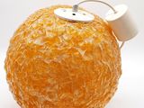 une orange déjà pelée, posée sur une surface blanche