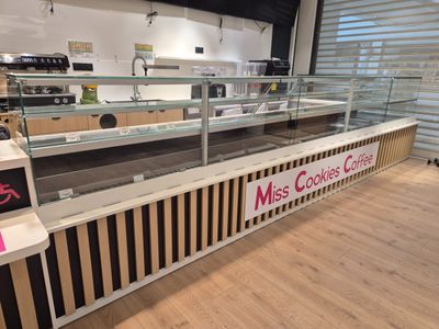 un comptoir en verre avec une enseigne indiquant « Miss Cookies Café »
