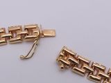 two pieces of gold bracelets and a clasp on a white surface