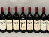 six bottles of red wine lined up in a row on a table