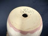 a white and pink vase with writing on it