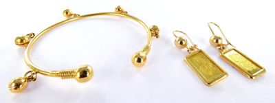 two pairs of gold earrings and a bracelet on a white surface
