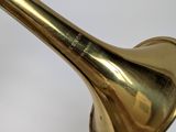 a brass trumpet that is sitting on a white surface