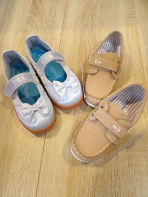 three pairs of children ' s shoes sitting on a wooden floor