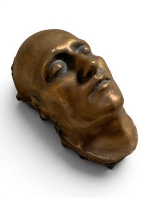 sculpture en bronze représentant la tête d'un homme sur un fond blanc