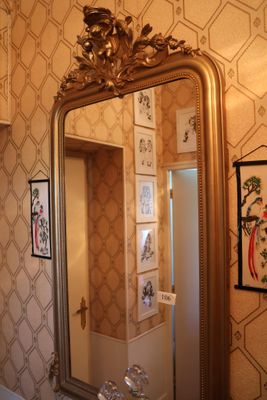 un miroir de salle de bains avec un cadre doré accroché au mur