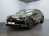 Une voiture noire est garée dans une grande pièce aux murs blancs.
