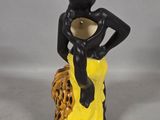 yellow and black figurine of a woman sitting on a tree stump