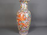 un vase orange et bleu orné d'un dragon, posé sur un fond gris