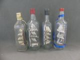 quatre bouteilles en verre contenant différents types de voiliers
