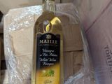 une bouteille d'huile d'olive dans une boîte posée par terre