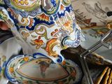 a person holding a teapot over a pile of plates