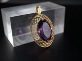 une photo d'un pendentif en pierre violette posé sur une boîte transparente