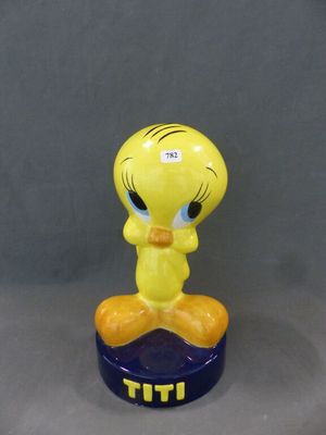 un gros plan sur une figurine représentant un oiseau jaune posé sur un socle bleu