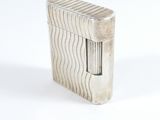 briquet argenté posé sur une surface blanche, avec un fond blanc