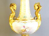 a gold vase with two cherns on it on a stand