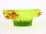 un vase vert contenant des fleurs orange, posé sur une surface blanche